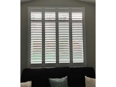 Shutter blinds over a black couch